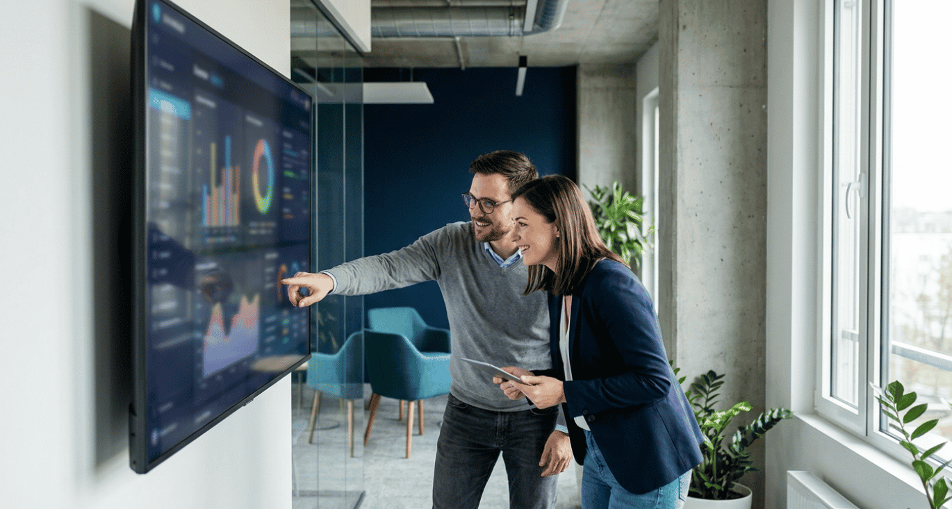 Two IT staff reviewing a single security management console in a mid-market office.