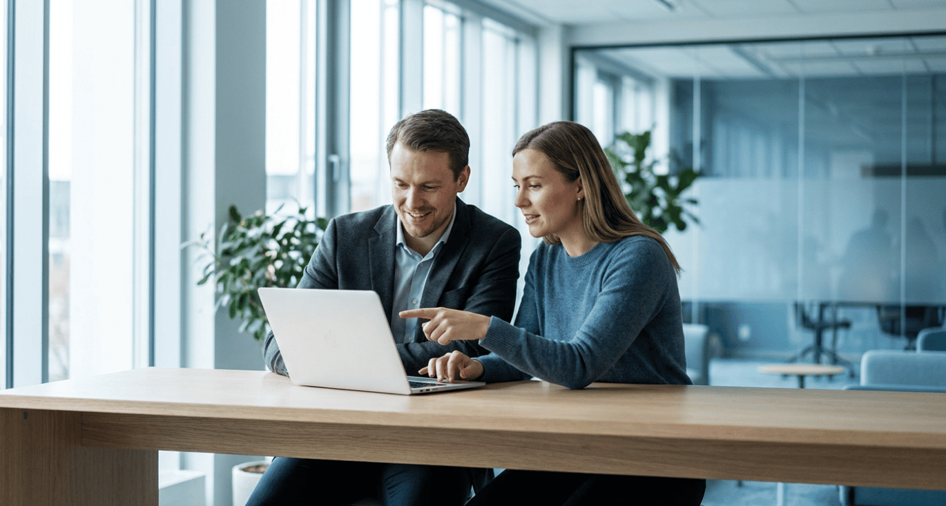 Two colleagues collaborating over a laptop in a modern office, representing the Jimber and Amotek partnership.