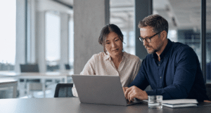 Two mid-market IT decision-makers comparing SASE options on a laptop in a modern European office