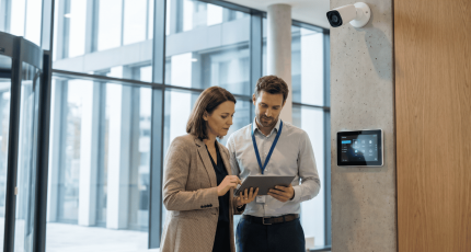 IT and facilities staff reviewing IP camera and building management system security in a European office.