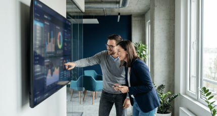 Two IT staff reviewing a single security management console in a mid-market office.